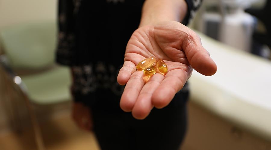 A hand holding fish oil supplement pills.